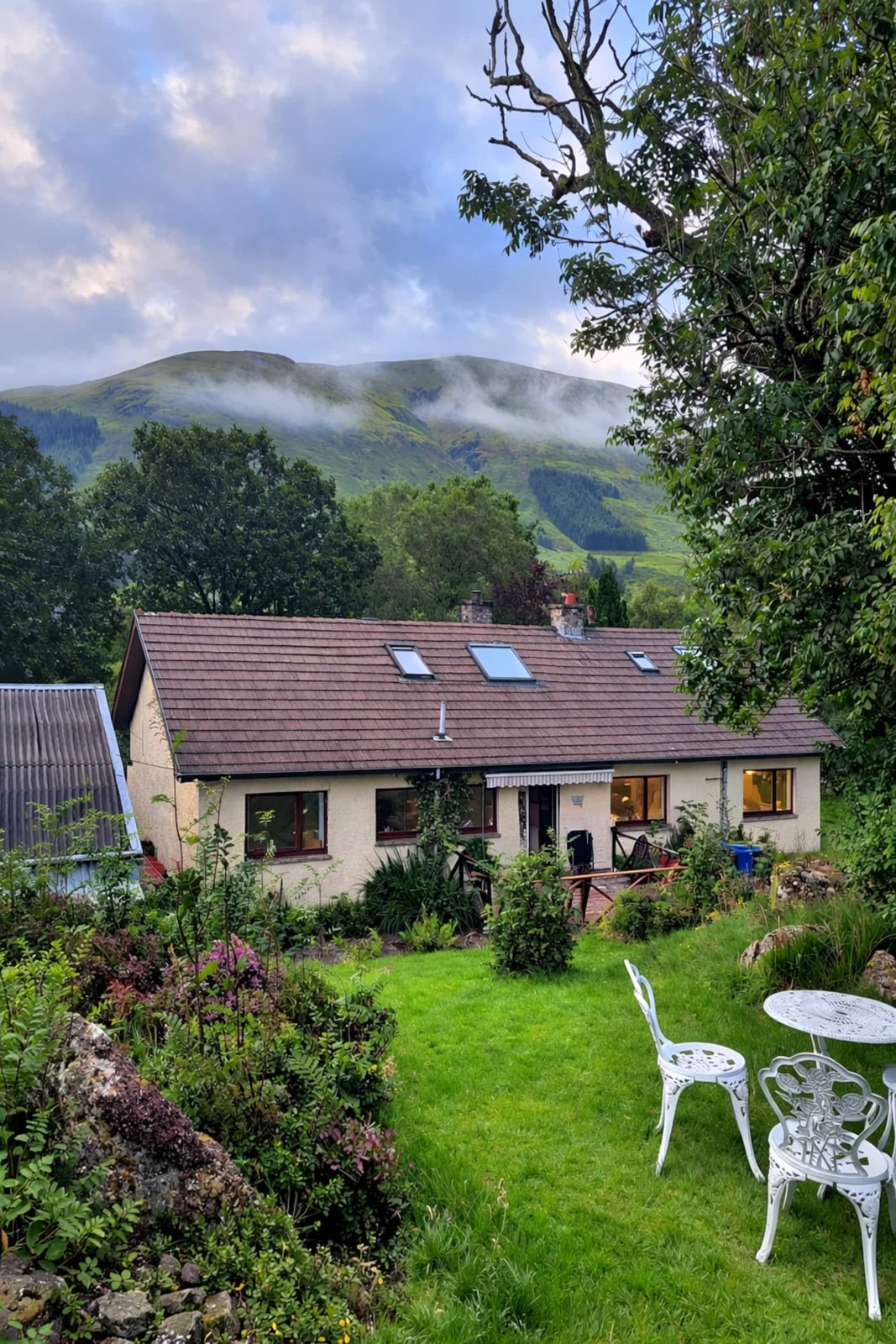 The whole house from the back garden, misty hills beyond